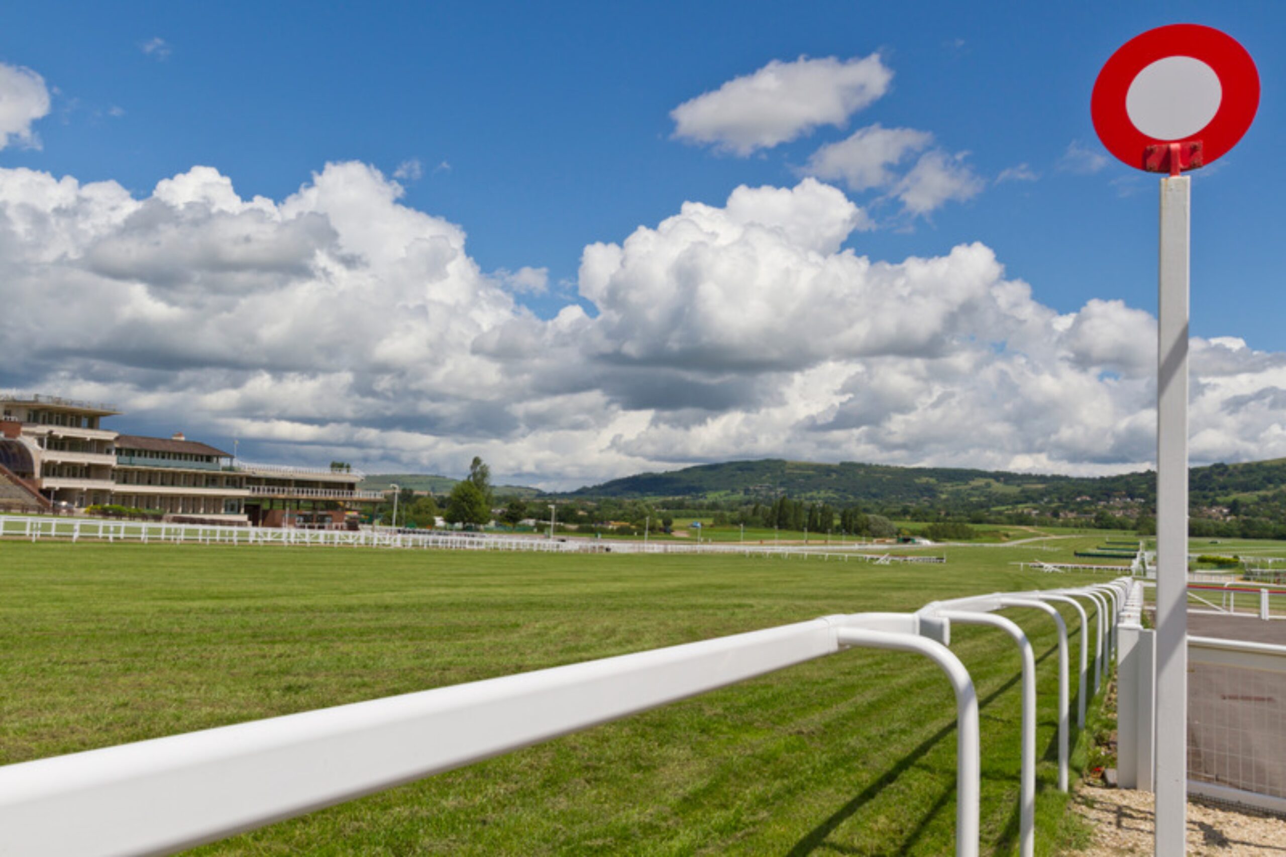 Winning post marker with racecourse grandstand and hills behind